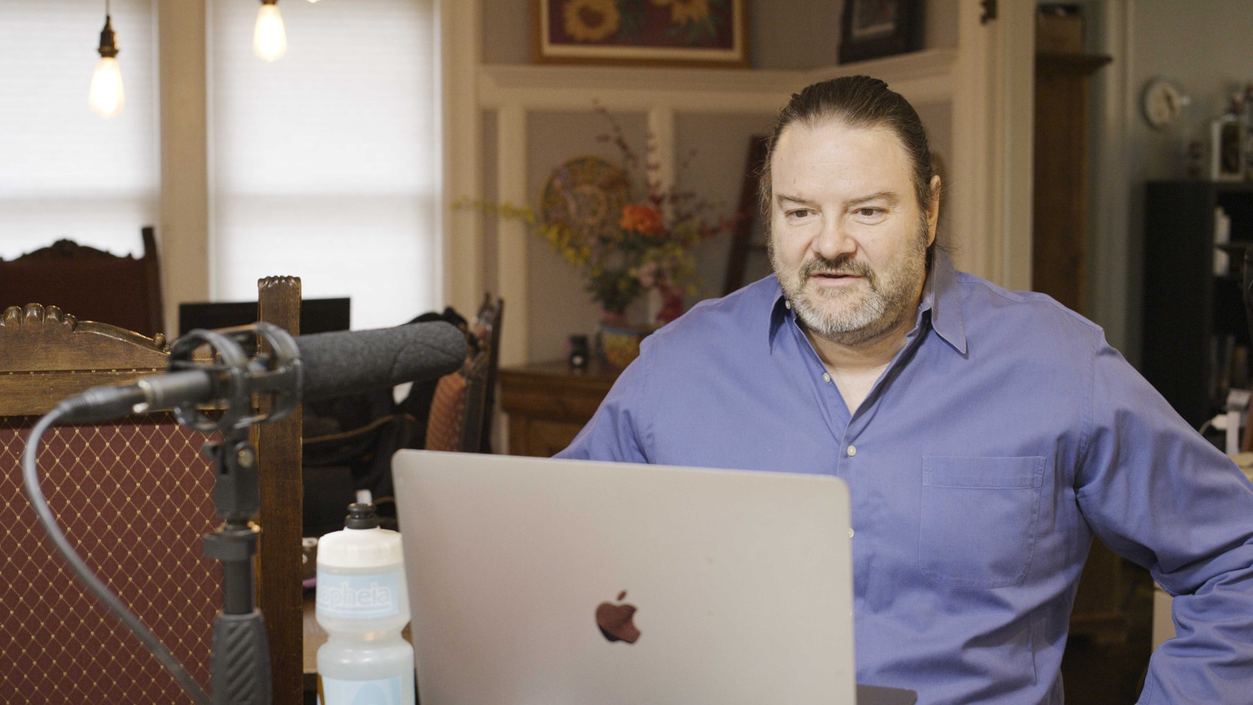 Christopher Henze working at his computer beside a microphone